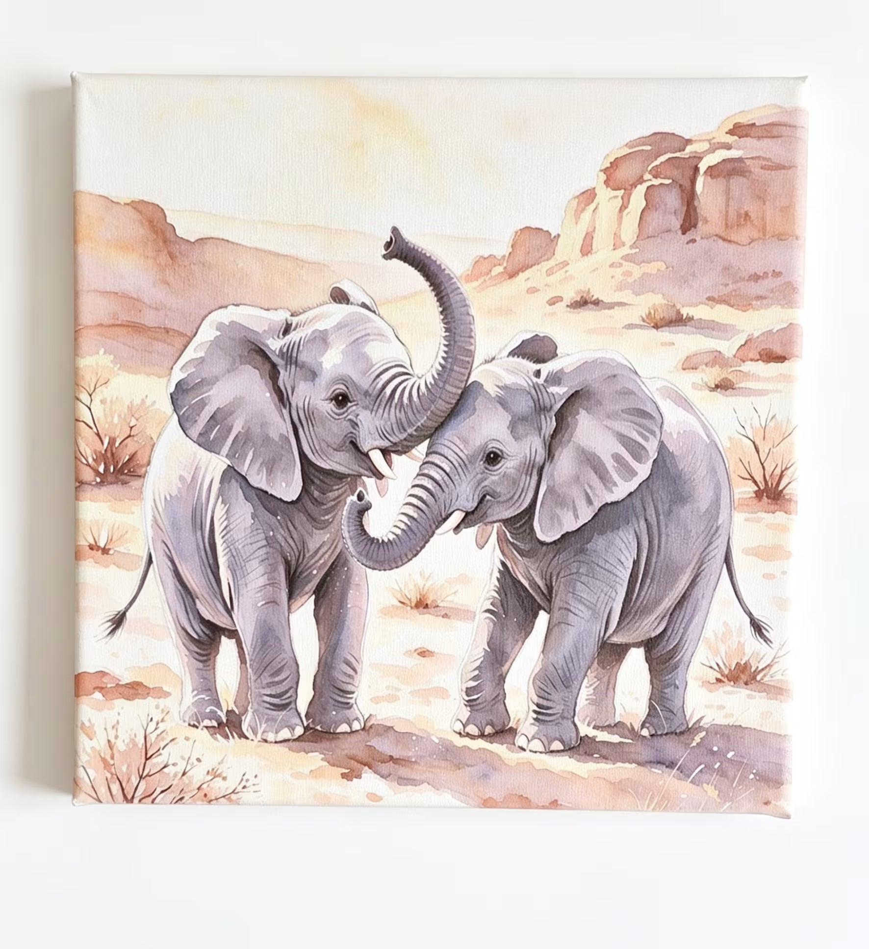 A square watercolor-style art print or canvas showing two gray elephants standing in a desert landscape with tan rocks and sparse shrubs, photographed against a plain white background.