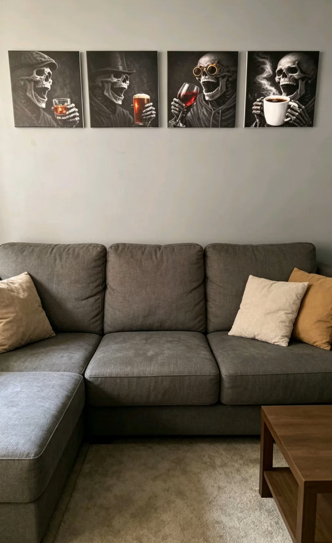 A gray sectional sofa in a living room setting, decorated with beige and mustard yellow pillows, with four black-and-white skeleton art prints hanging on the wall above.