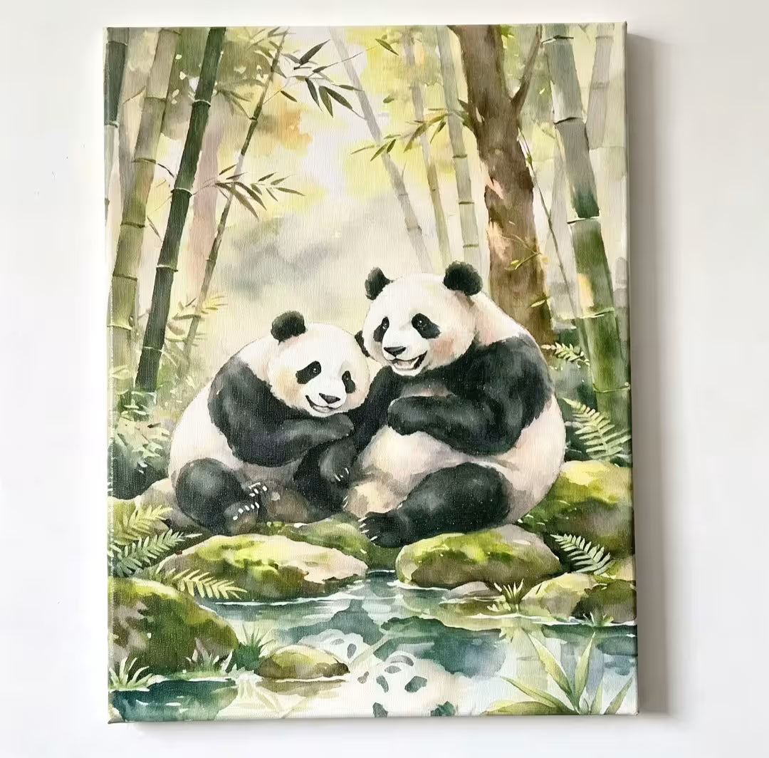 Watercolor painting of two pandas hugging in a bamboo forest, displayed on a canvas against a plain white wall.