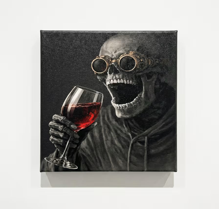 A square canvas wall art print featuring a black-and-white skeletal figure wearing round goggles and holding a glass of red wine, shown hanging against a light gray wall.